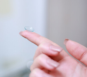 A close-up shot of a contact lens on a person's fingertip