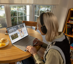 A woman using a Dell laptop on a dining table